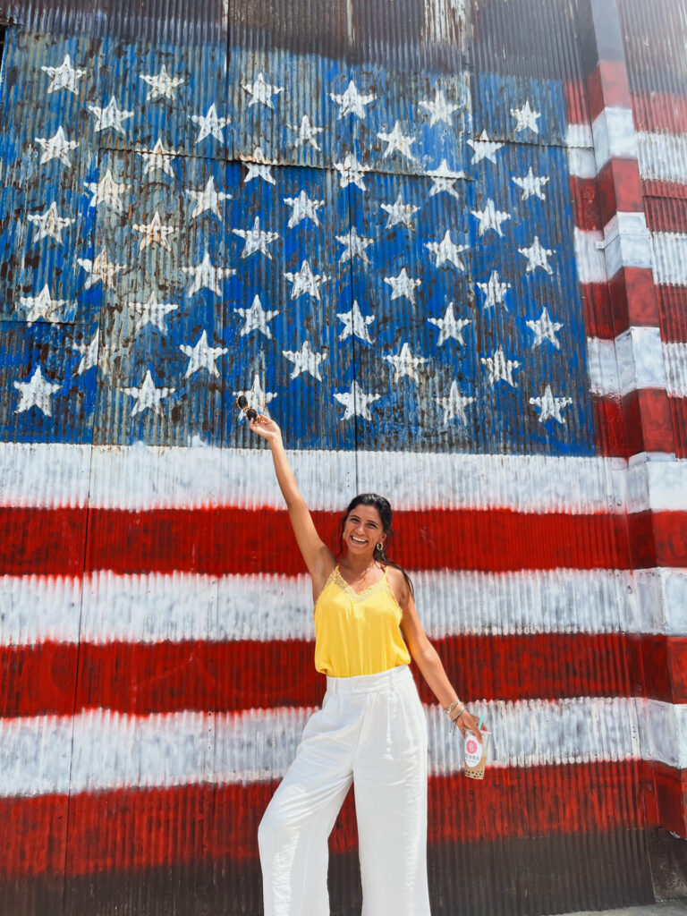 Travel Guides 50 girl in front of us flag mural